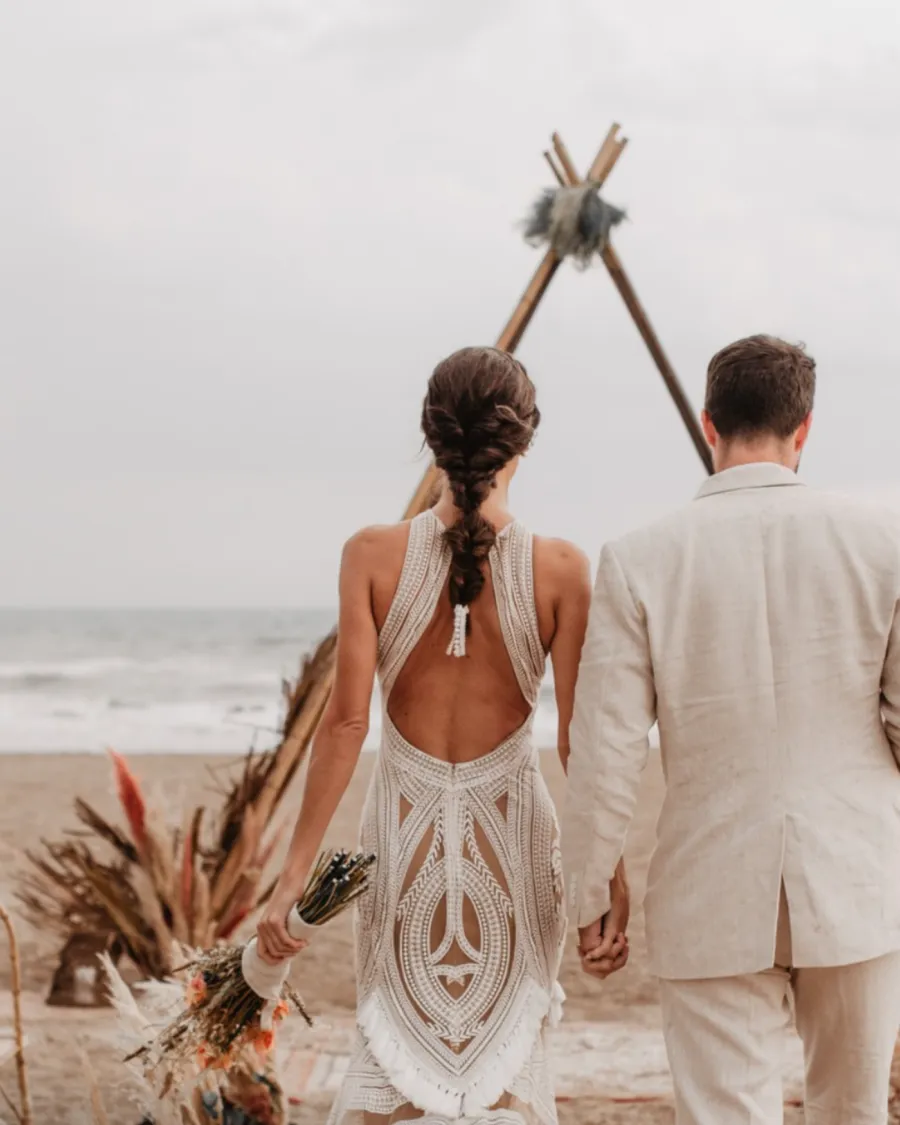 Novios caminando por la playa hacia el altar