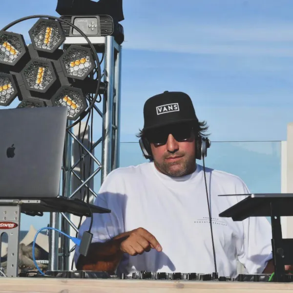 DJ con gorra pasando música frente al mar